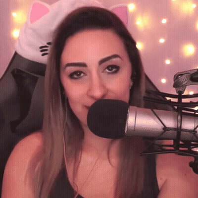 A Woman Wearing Headphones And A Cat Ear Hat Is Talking Into A Microphone GIF