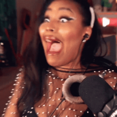 A Woman Wearing Headphones And A Headband Is Making A Funny Face In Front Of A Microphone GIF