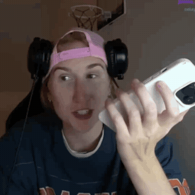 a woman wearing headphones and a pink hat is holding a phone