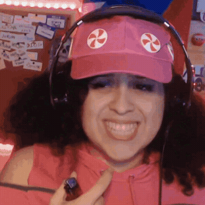 A Woman Wearing Headphones And A Pink Hat With A Candy Cane On It GIF