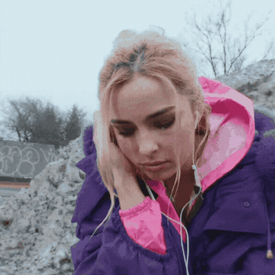 A Woman Wearing Headphones And A Purple Jacket With A Pink Hood GIF