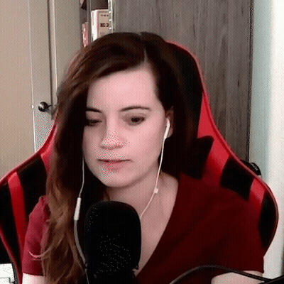 A Woman Wearing Headphones And A Red Shirt Is Sitting In A Red Chair . GIF