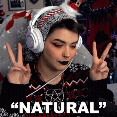 A Woman Wearing Headphones And A Santa Hat Is Giving A Peace Sign With The Words " Natural " Below Her GIF
