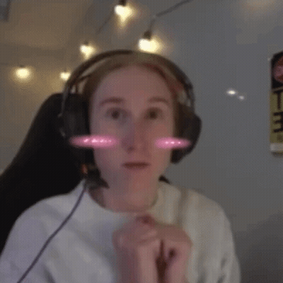 A Woman Wearing Headphones And A White Shirt Is Smiling GIF