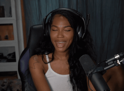 A Woman Wearing Headphones And A White Tank Top Smiles While Sitting In Front Of A Microphone GIF