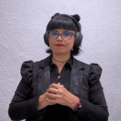 A Woman Wearing Headphones And Glasses Is Making A Gesture GIF