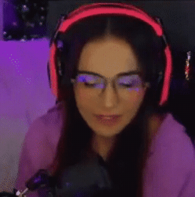 A Woman Wearing Headphones And Glasses Is Playing A Video Game . GIF