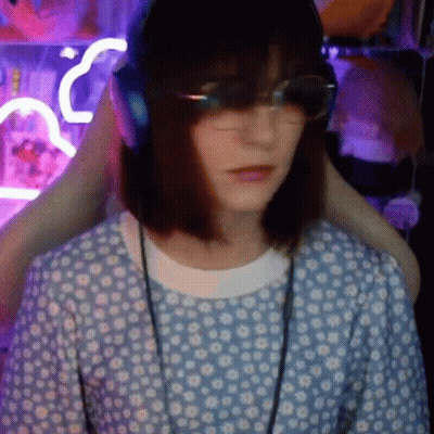 A Woman Wearing Headphones And Glasses Is Sitting In A Chair In A Room . GIF