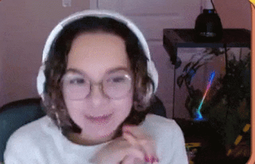A Woman Wearing Headphones And Glasses Is Sitting In Front Of A Computer Monitor . GIF