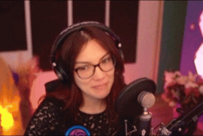 A Woman Wearing Headphones And Glasses Is Sitting In Front Of A Microphone In A Recording Studio . GIF
