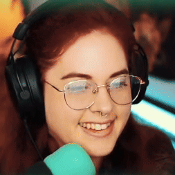 A Woman Wearing Headphones And Glasses Is Smiling In Front Of A Blue Microphone . GIF