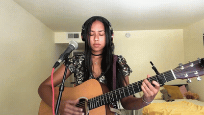 A Woman Wearing Headphones And Playing An Acoustic Guitar GIF