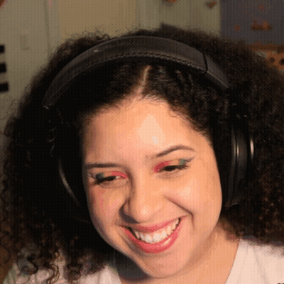 A Woman Wearing Headphones And Red Eye Shadow Smiles GIF