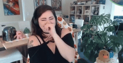 A Woman Wearing Headphones Is Covering Her Nose While Sitting In A Chair In A Living Room . GIF