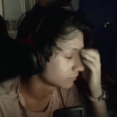 A Woman Wearing Headphones Is Crying While Sitting In Front Of A Computer Screen . GIF