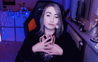 A Woman Wearing Headphones Is Holding A Candy Cane In Her Hand GIF