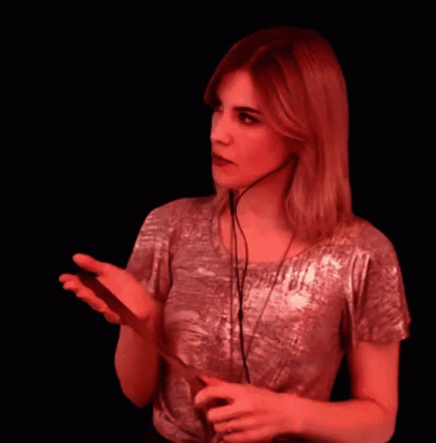 A Woman Wearing Headphones Is Holding A Cell Phone In Her Hand GIF