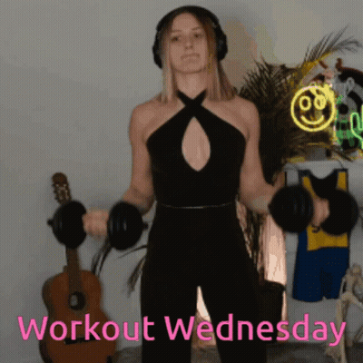 A Woman Wearing Headphones Is Lifting Dumbbells And The Words Workout Wednesday Are Visible Behind Her GIF