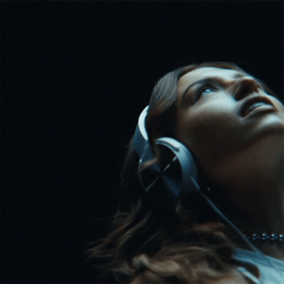 A Woman Wearing Headphones Is Listening To Music GIF