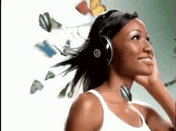 A Woman Wearing Headphones Is Listening To Music With Butterflies Flying In The Background . GIF