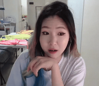 A Woman Wearing Headphones Is Looking At The Camera With Her Hand On Her Chin GIF