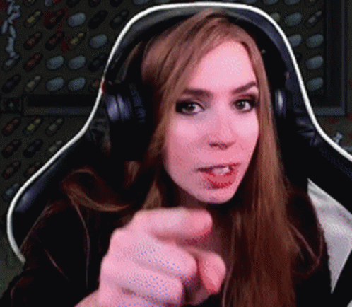 A Woman Wearing Headphones Is Pointing Her Finger At The Camera GIF