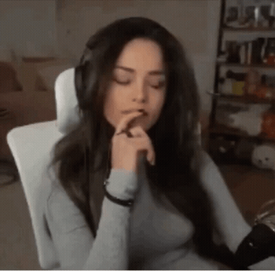 A Woman Wearing Headphones Is Sitting In A Chair With Her Eyes Closed And Her Hands On Her Chin . GIF