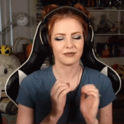 A Woman Wearing Headphones Is Sitting In A Gaming Chair And Making A Face . GIF