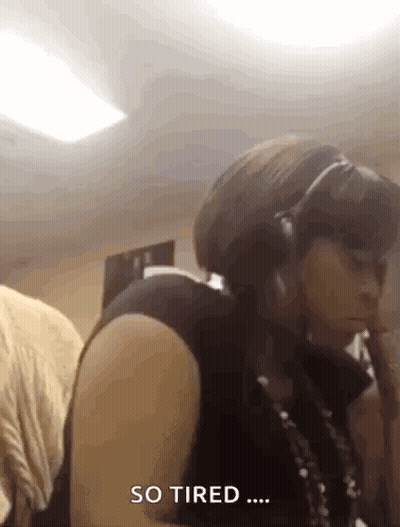 A Woman Wearing Headphones Is Sitting In A Room And Says So Tired . GIF
