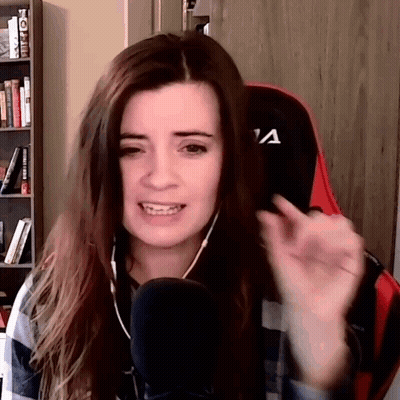 A Woman Wearing Headphones Is Sitting In Front Of A Microphone And Making A Face . GIF