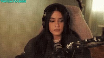 A Woman Wearing Headphones Is Sitting In Front Of A Microphone In A Chair . GIF