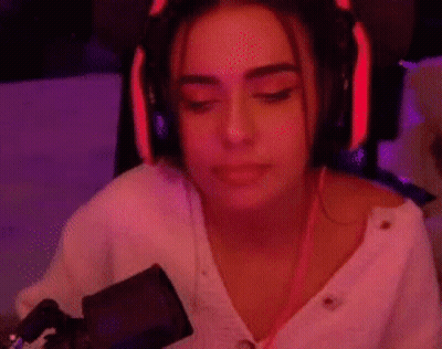 A Woman Wearing Headphones Is Sitting In Front Of A Microphone In A Room . GIF