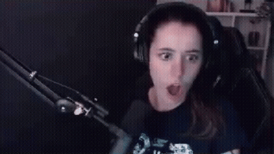 A Woman Wearing Headphones Is Sitting In Front Of A Microphone Making A Funny Face . GIF