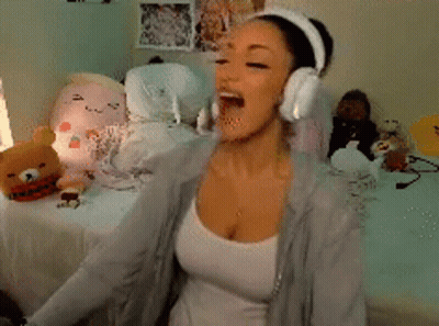 A Woman Wearing Headphones Is Sitting On A Bed In Front Of Stuffed Animals GIF