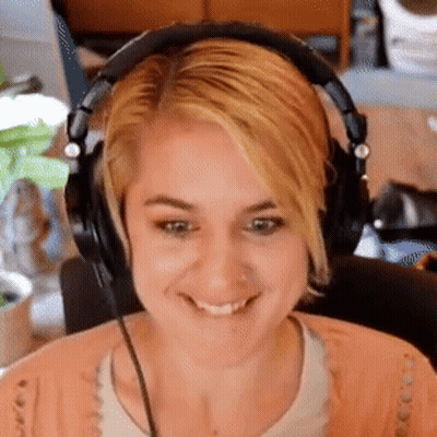 A Woman Wearing Headphones Is Smiling And Making A Funny Face GIF