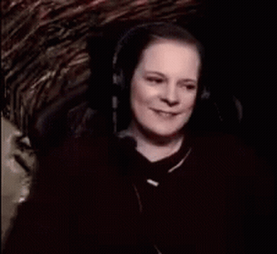 A Woman Wearing Headphones Is Smiling And Says " Witch Cackling " GIF