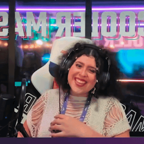 A Woman Wearing Headphones Is Smiling In Front Of A Sign That Says ' Game 100 ' GIF