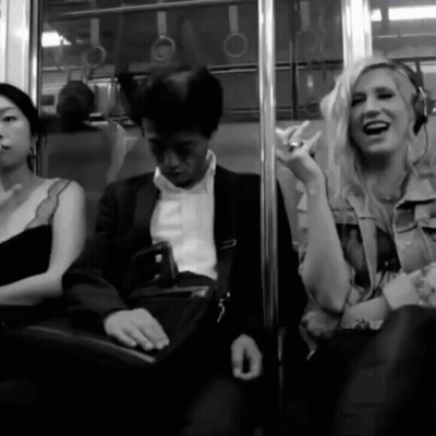 A Woman Wearing Headphones Laughs While Sitting Next To A Man GIF