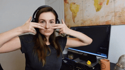 A Woman Wearing Headphones Making A Face In Front Of A Computer Monitor GIF