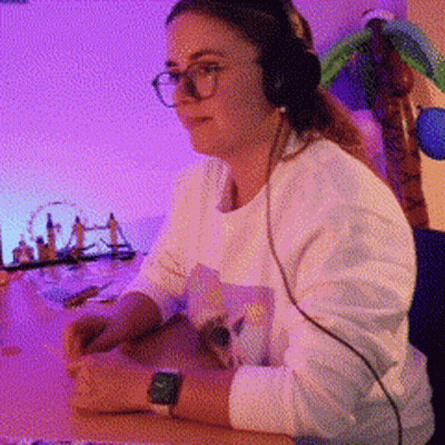 A Woman Wearing Headphones Sits At A Desk GIF