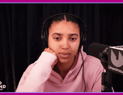 A Woman Wearing Headphones Sits In Front Of A Microphone That Says Unanimity GIF