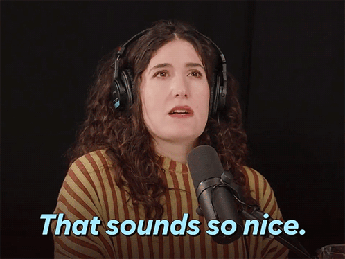 A Woman Wearing Headphones Stands In Front Of A Microphone With The Words That Sounds So Nice Below Her GIF