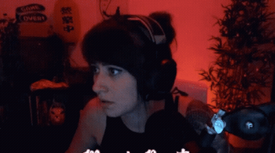 A Woman Wearing Headphones With A Sign That Says Come Over In The Background GIF
