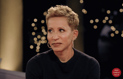 A Woman Wearing Hoop Earrings And A Black Shirt With A Red Circle That Says Red Table Talk GIF