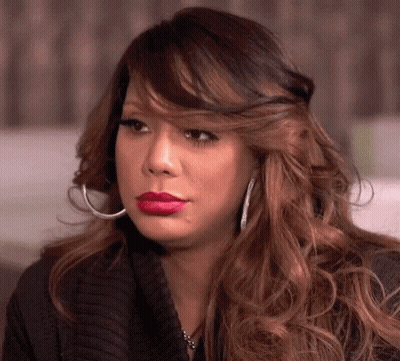 A Woman Wearing Hoop Earrings And Red Lipstick Is Looking At The Camera . GIF
