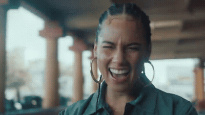 A Woman Wearing Hoop Earrings Is Laughing With Her Eyes Closed And Her Mouth Open . GIF