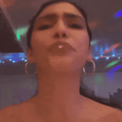 A Woman Wearing Hoop Earrings Is Making A Face GIF