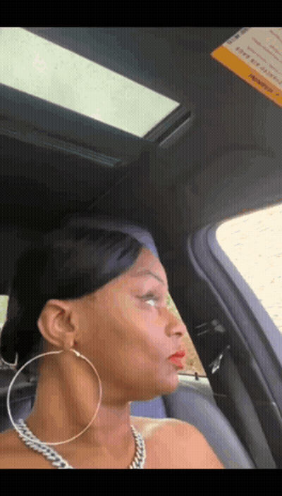 A Woman Wearing Hoop Earrings Is Sitting In A Car With A Sunroof GIF