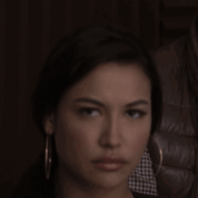 A Woman Wearing Hoop Earrings Looks At The Camera With A Serious Look On Her Face GIF