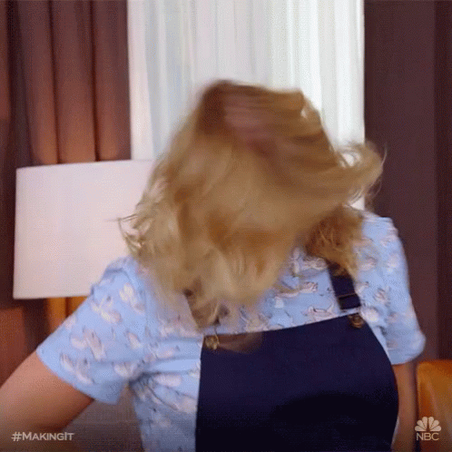 A Woman Wearing Overalls And A Blue Shirt Is Making A Funny Face With Her Hair GIF
